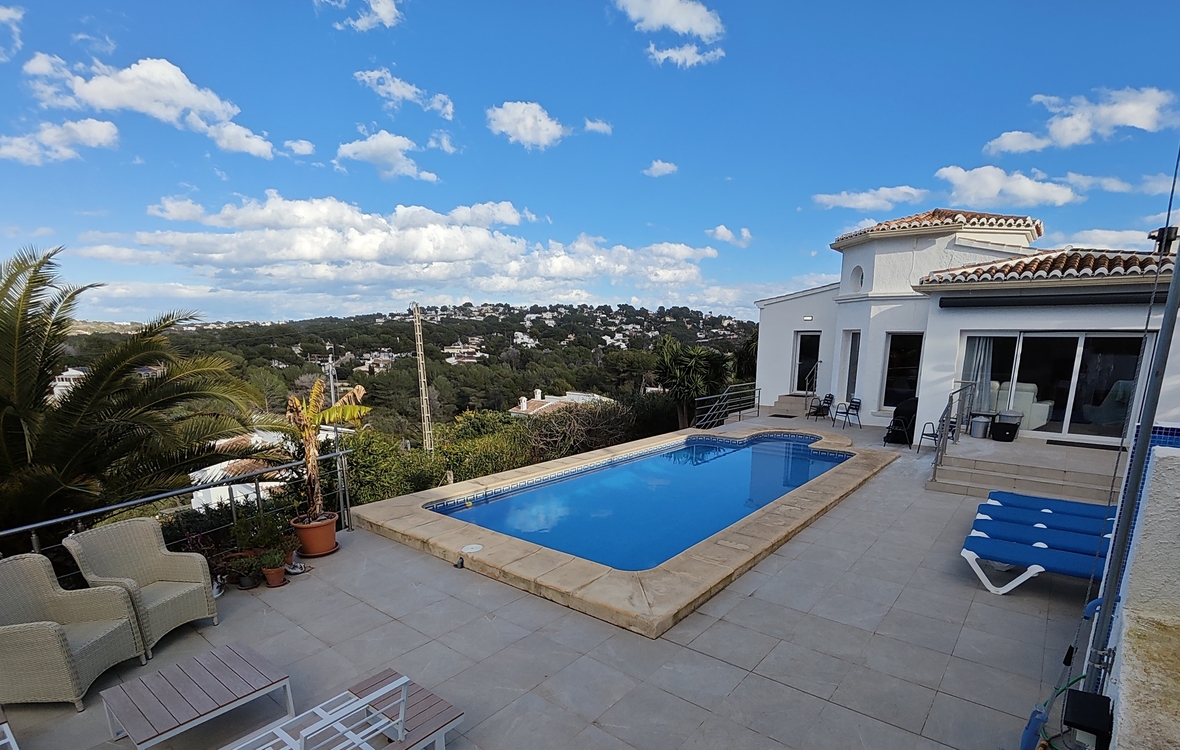 Terraza exterior con piscina rectangular, coronación de piedra y zona de solárium con vistas panorámicas al valle y colinas residenciales circundantes.