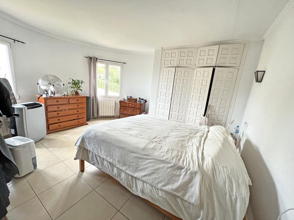 Dormitorio con amplios armarios empotrados de diseño panelado, suelos de gres y luz natural. Incluye mobiliario de madera y calefacción por radiador.