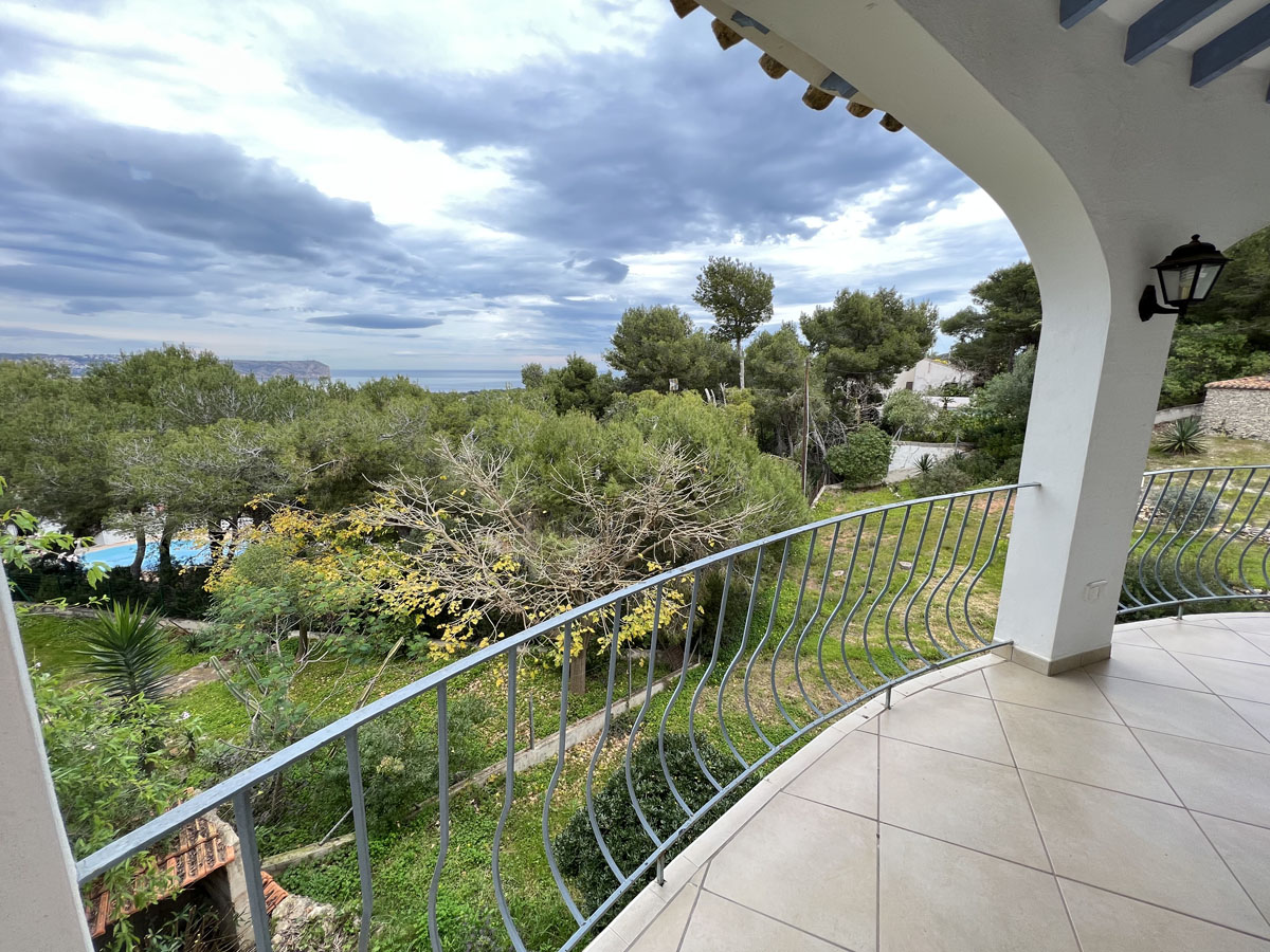 Terraza cubierta con suelos cerámicos y arcos blancos, ofreciendo vistas panorámicas al mar Mediterráneo y al Cabo San Antonio entre la vegetación.