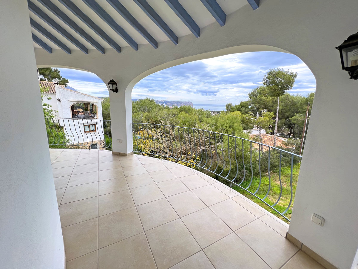 Terraza cubierta con vigas de madera en azul claro, suelo de gres y barandilla curva con vistas panorámicas al mar y al Cabo San Antonio.