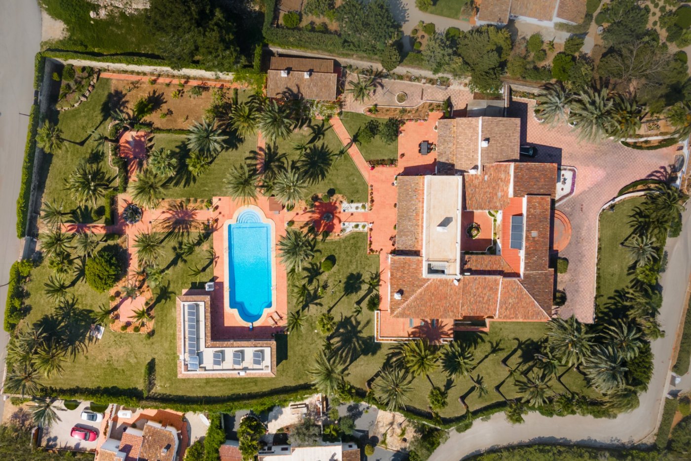 Vista aérea de la parcela de 5.835m2 que destaca la villa con patio central, la piscina de 16x7m y el jardín mediterráneo con más de 80 palmeras.