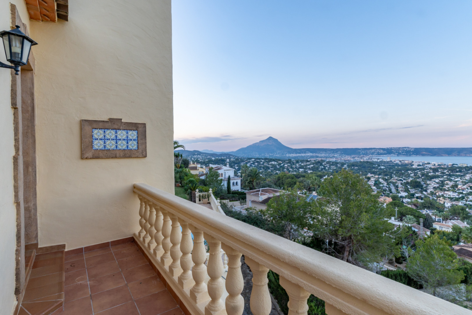 Terraza superior con suelo de barro cocido y balaustrada, con amplias vistas a la bahía de Jávea y el macizo del Montgó al fondo.