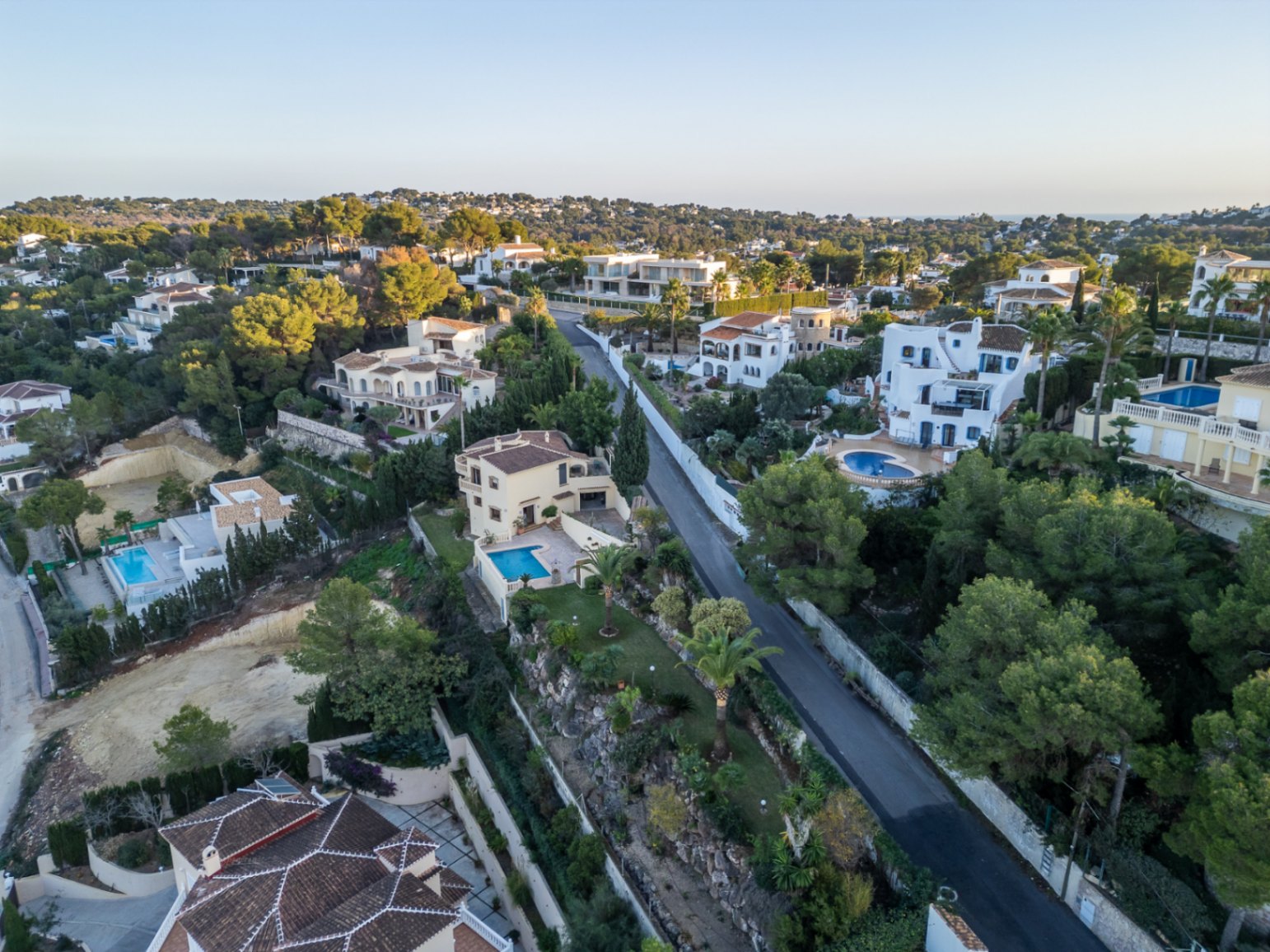 Vista aérea de la urbanización Costa Nova Panorama en Jávea, mostrando villas de estilo mediterráneo rodeadas de pinos, jardines privados y piscinas individuales.