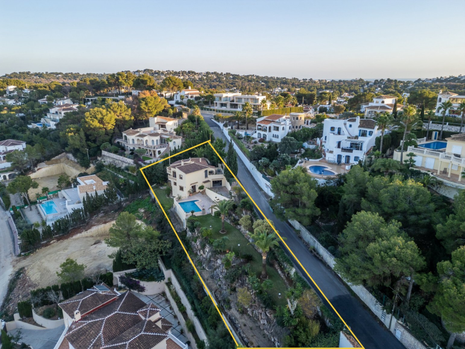 Vista aérea de la villa delimitada, destacando su parcela aterrazada con piscina, jardín mediterráneo y ubicación elevada en la zona de Costa Nova Panorama.