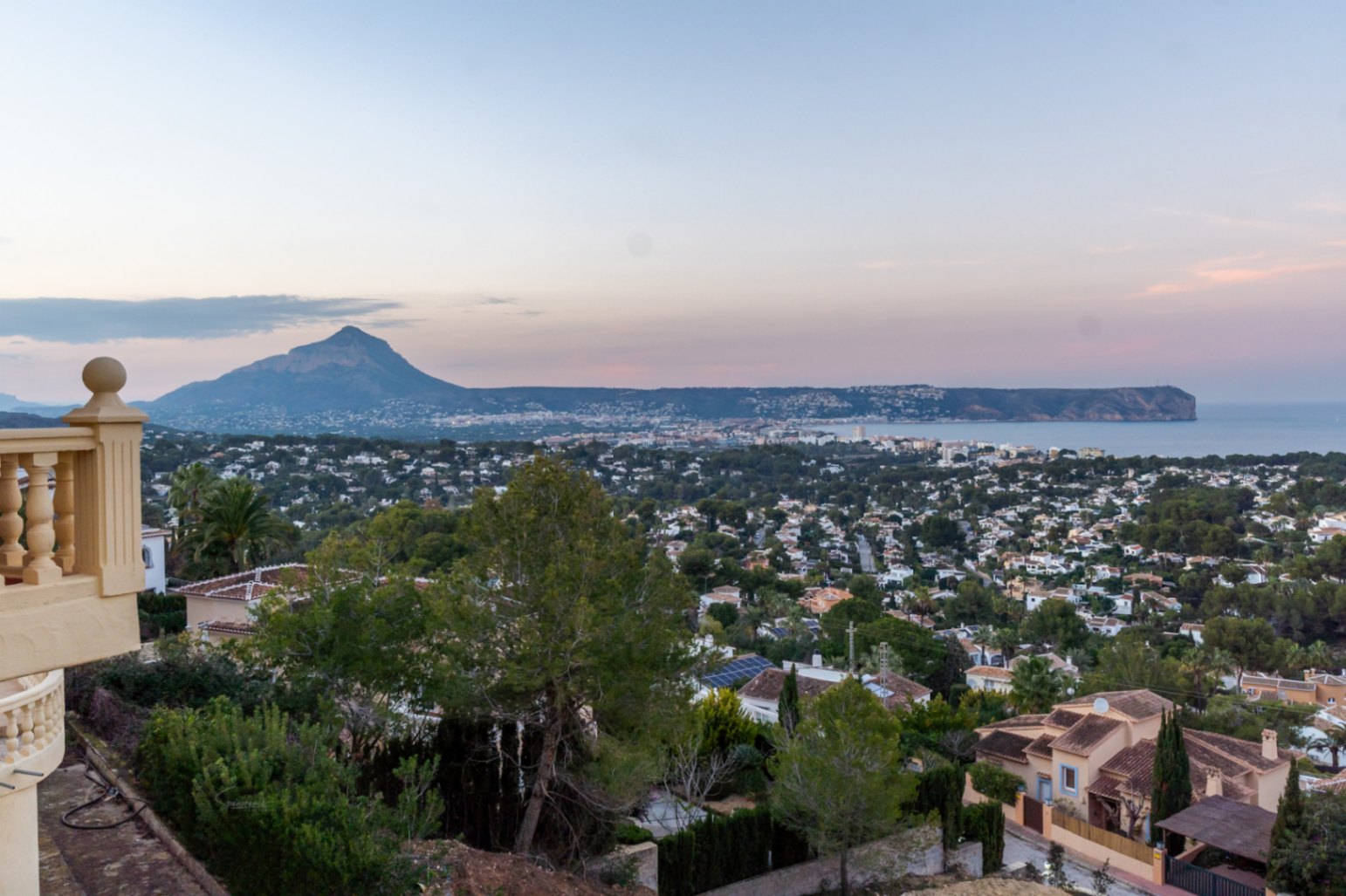 Vistas panorámicas desde la terraza elevada hacia la bahía de Jávea, el Montgó y el Cabo San Antonio al atardecer, rodeado de vegetación mediterránea.