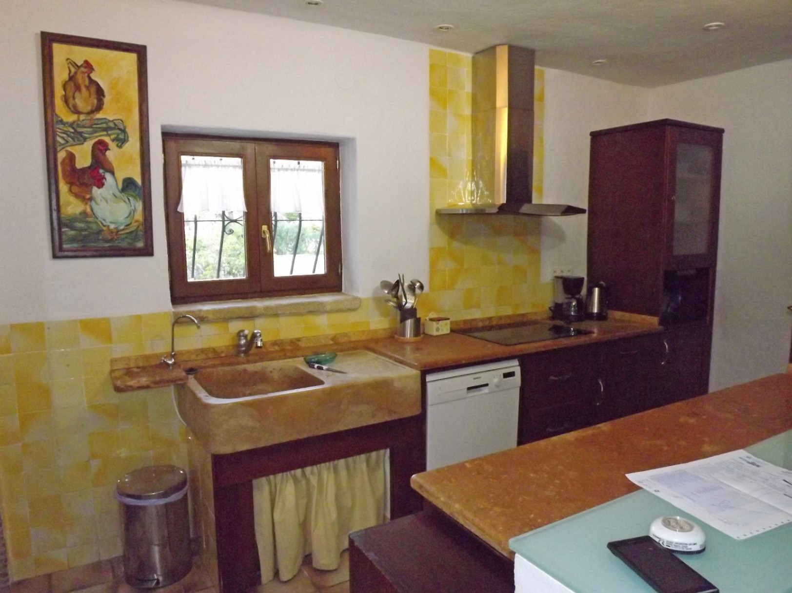 Cocina de estilo rústico con fregadero de piedra natural, azulejos en tonos amarillos, mobiliario de madera oscura y encimera de mármol bajo iluminación empotrada.