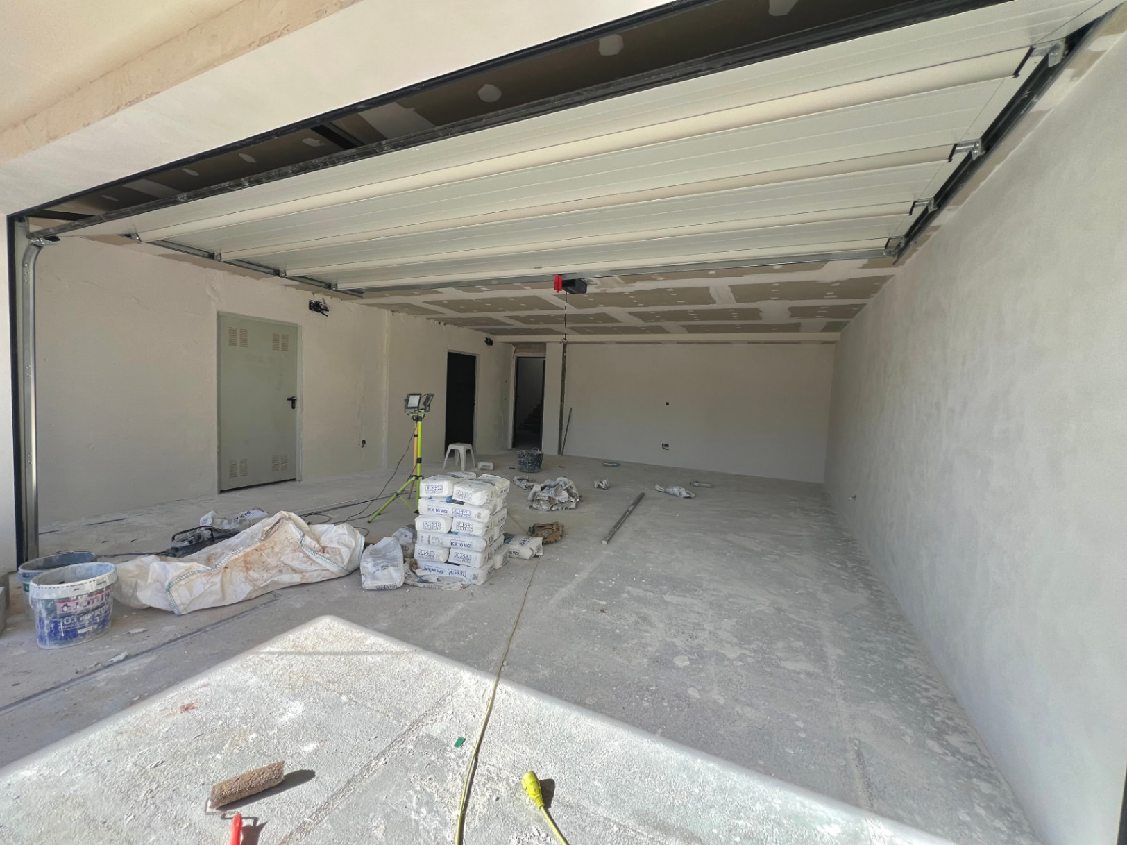 Amplio garaje en fase de construcción con puerta seccional automática, suelos de hormigón y acceso directo al interior de la villa en Jávea.