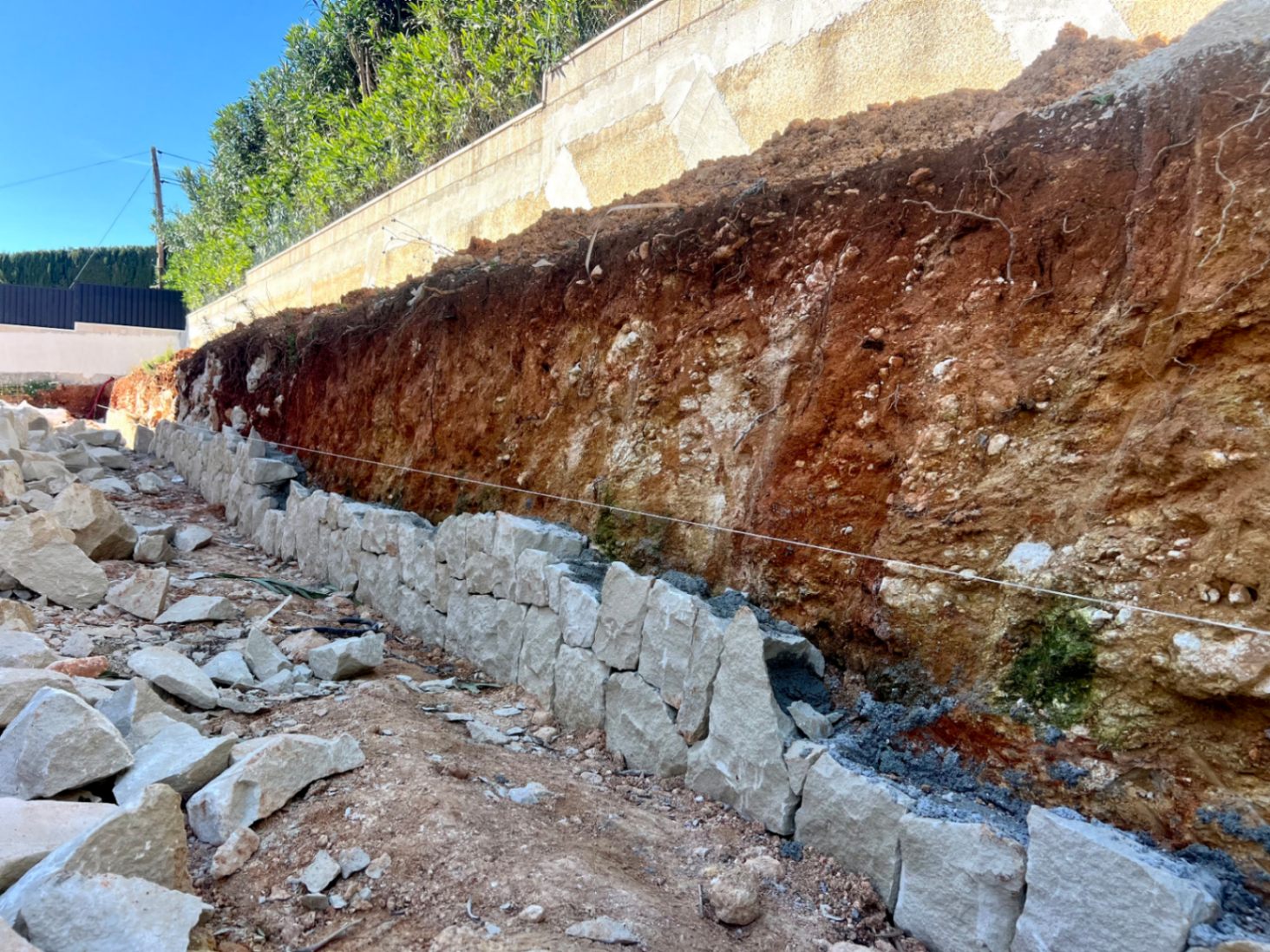 Inicio de las obras con la construcción de muros de contención en piedra natural, siguiendo técnicas tradicionales para asegurar la nivelación del terreno.