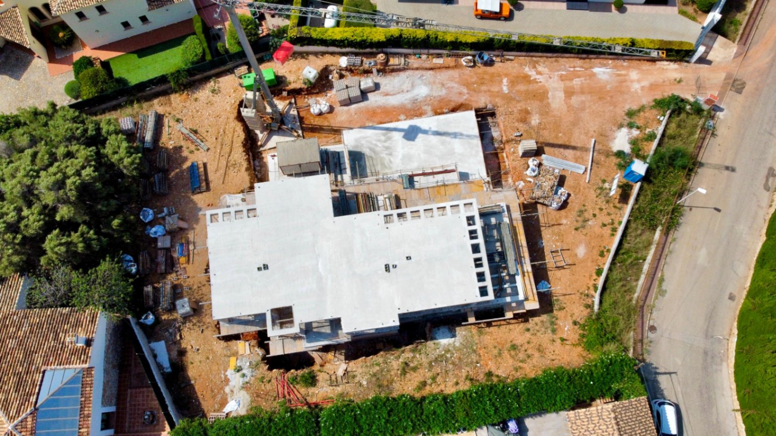 Vista aérea del progreso de construcción sobre la parcela plana en El Garroferal, mostrando la estructura de hormigón y la grúa en el sitio de obra.
