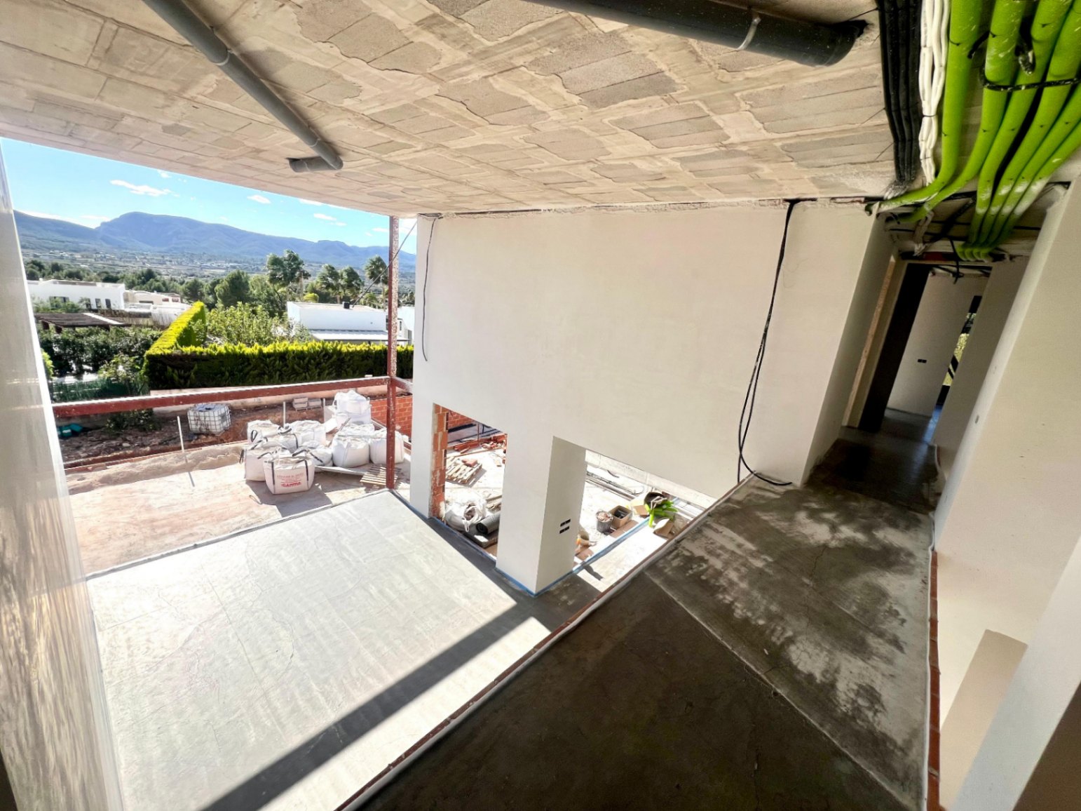 Vista del proceso de construcción de la planta superior, mostrando el espacio de doble altura y las vistas despejadas hacia el Montgó y el entorno natural de Jávea.