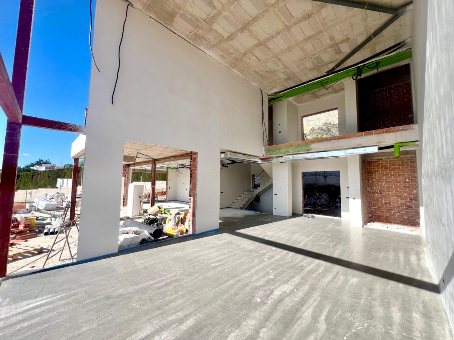 Vista interior de la estructura en construcción con techos de doble altura y huecos para grandes ventanales que aportan luz natural.