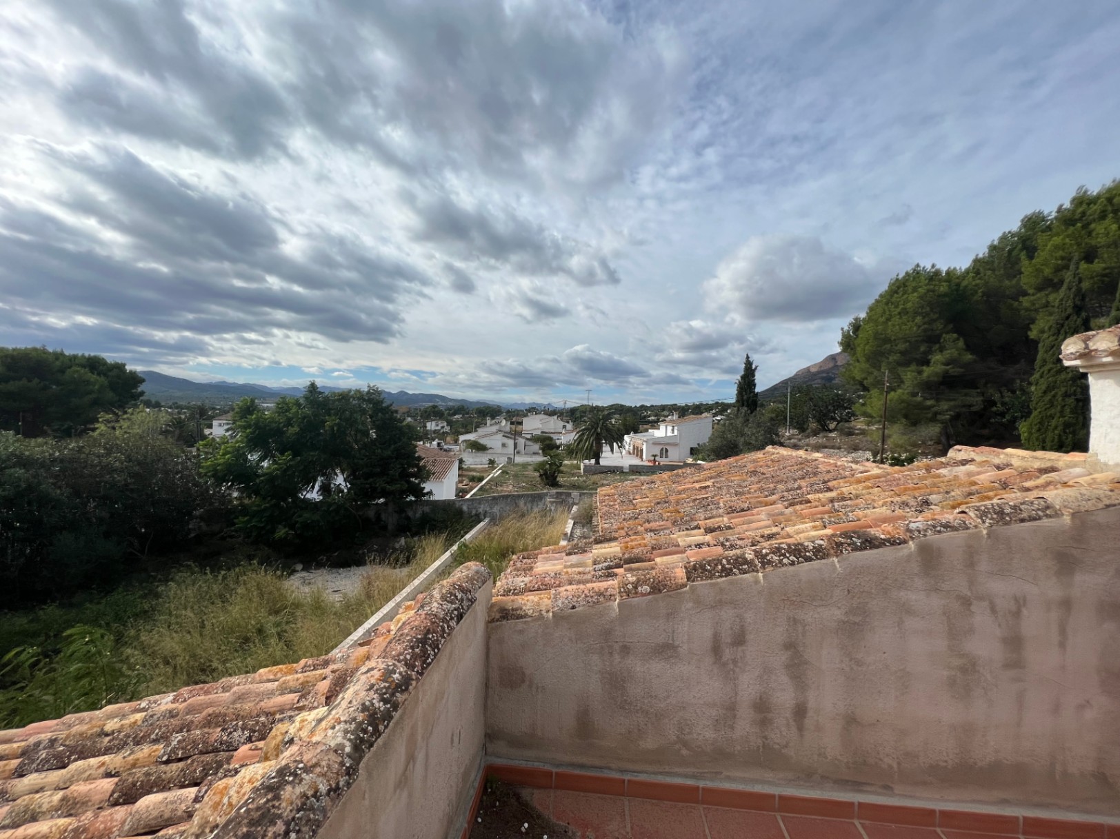 Vistas despejadas desde la terraza superior hacia el valle, mostrando la arquitectura tradicional de teja y el entorno verde de la zona del Montgó en Jávea.