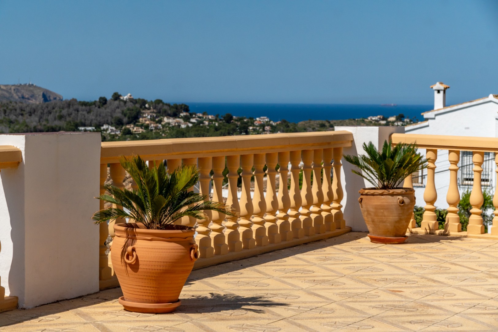 Terraza con suelo cerámico decorado y balaustrada clásica, ofreciendo vistas panorámicas al mar Mediterráneo y al entorno natural de Jávea.