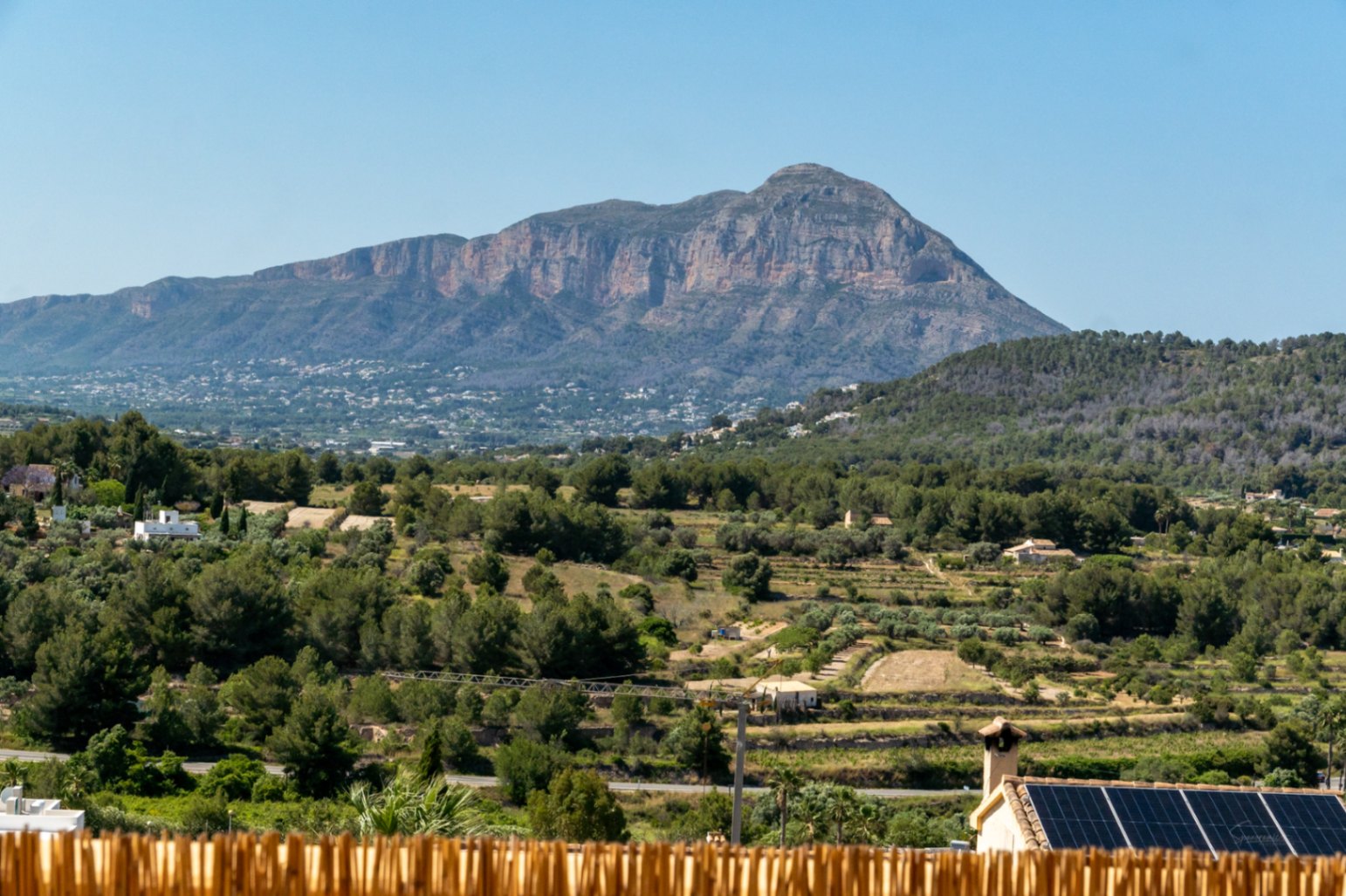 Vista panorámica del macizo del Montgó desde la propiedad, con el valle mediterráneo en primer plano y tejado equipado con placas solares fotovoltaicas.