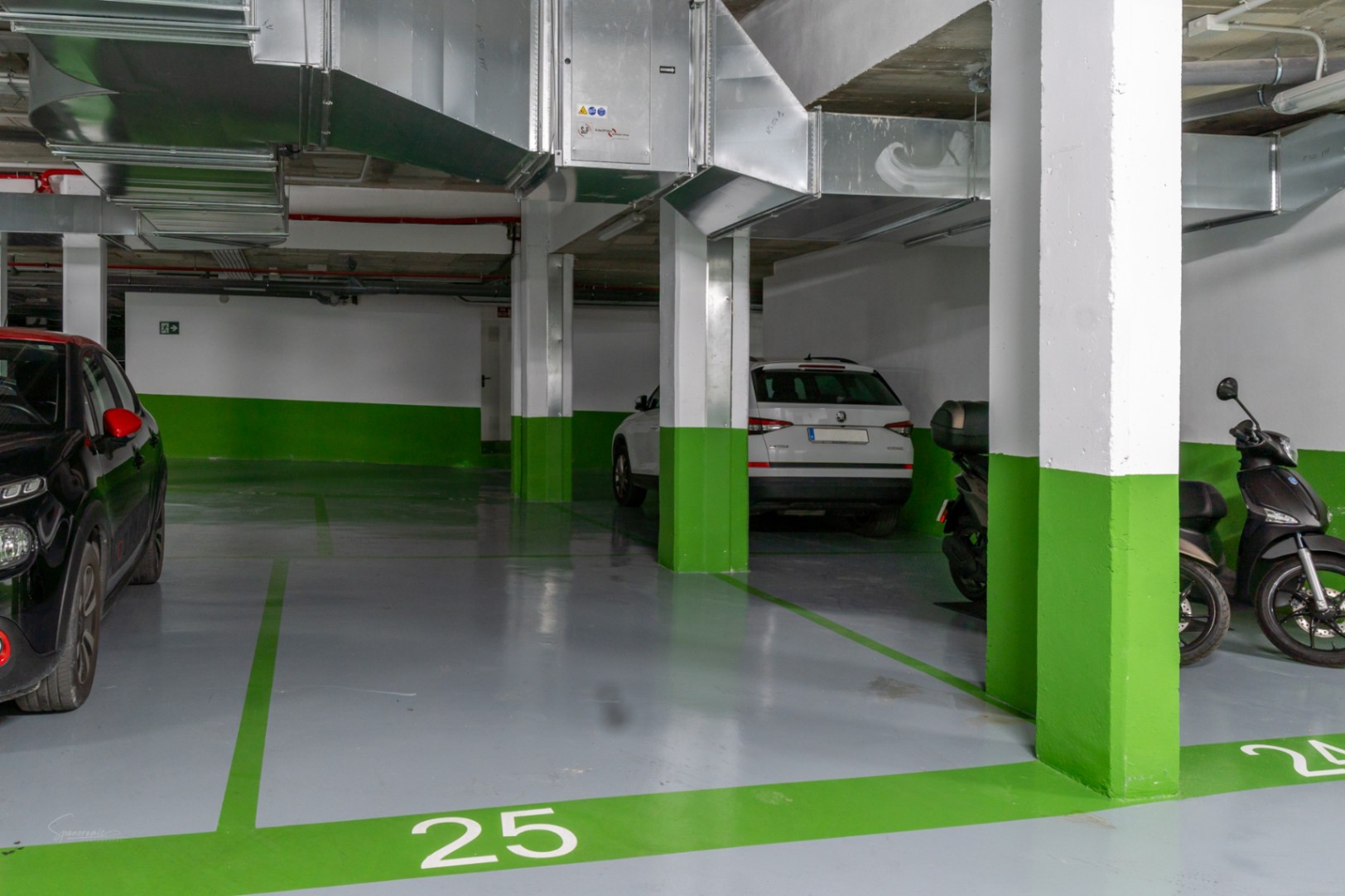 Plaza de garaje subterránea numerada con suelo de resina gris y señalización en verde, equipada con modernos sistemas de ventilación y fácil maniobrabilidad.