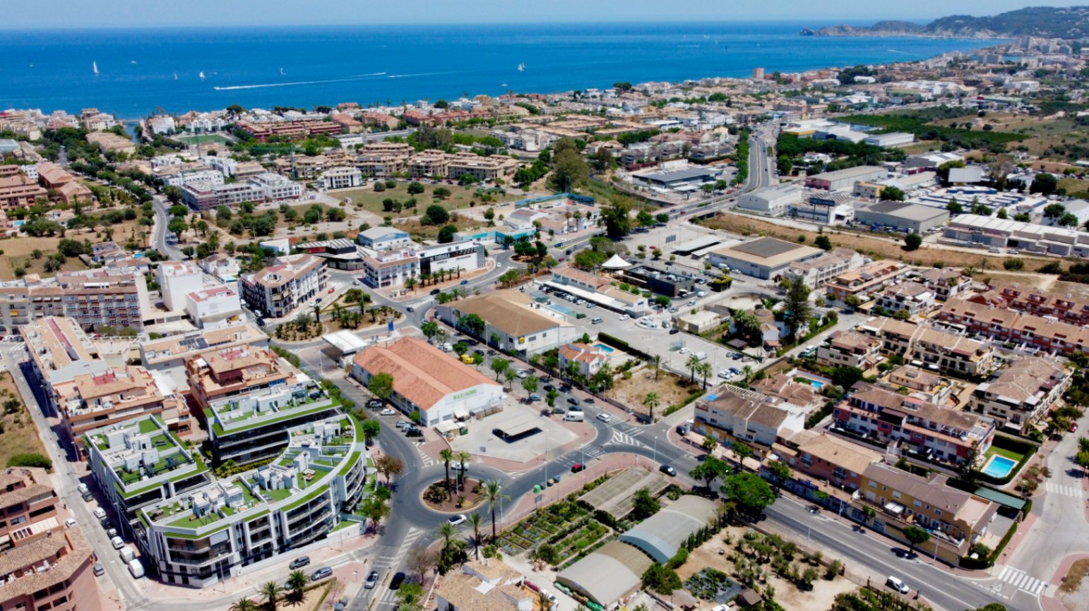 Vista aérea que destaca la arquitectura curva y las cubiertas ajardinadas del edificio, ubicado estratégicamente entre el casco antiguo de Jávea y la zona del puerto.