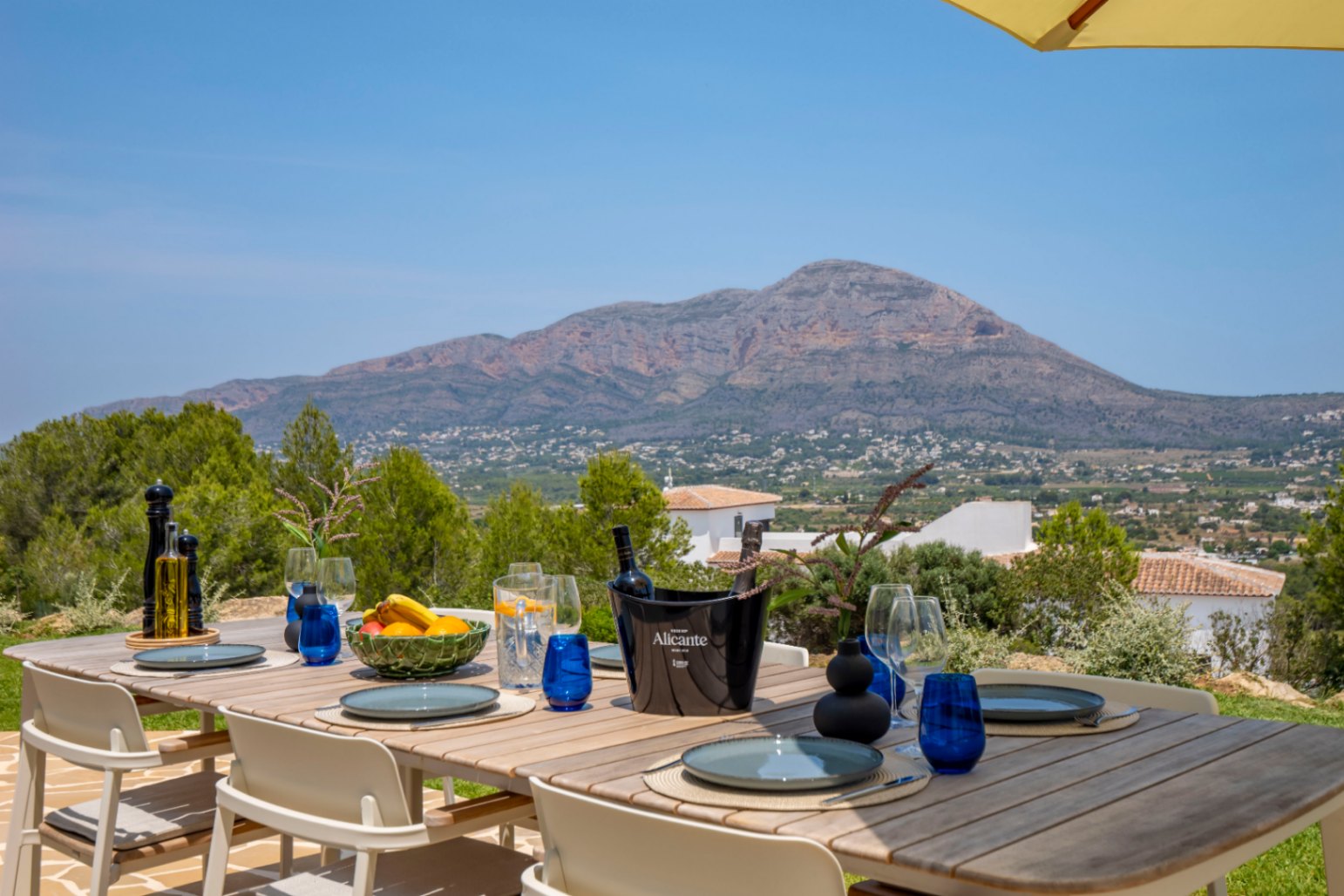 Comedor exterior con mesa de madera y vistas a la montaña en Jávea.