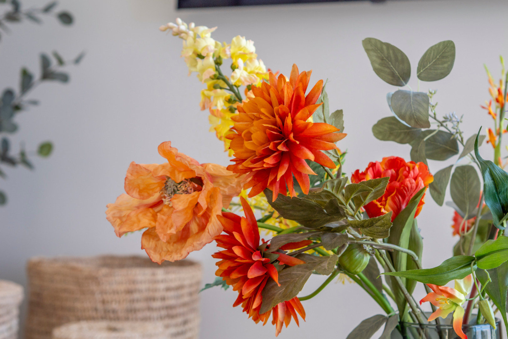Detalle floral con dalia naranja y amapola en jarrón, aportando un toque de color al interior.