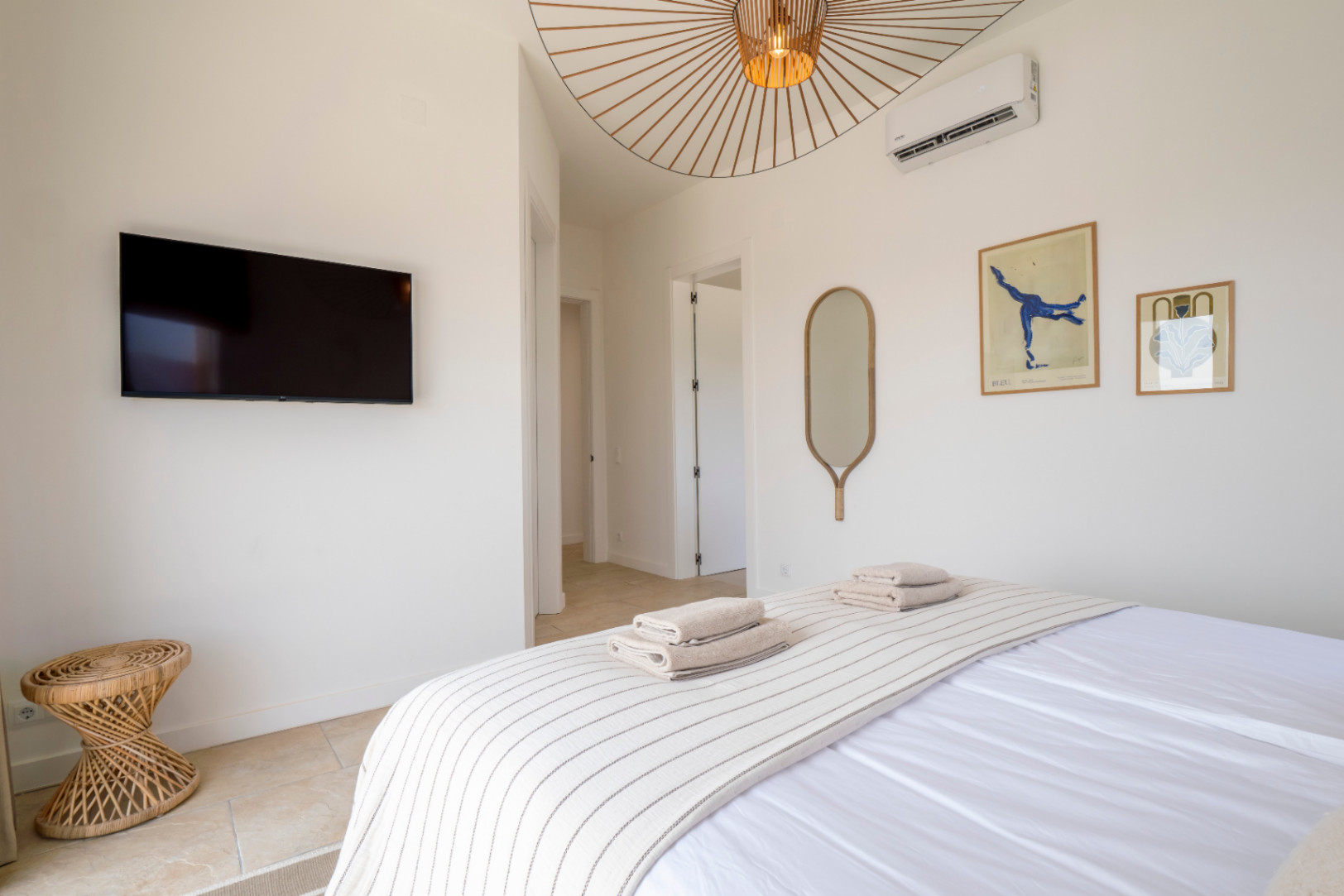 Dormitorio luminoso con TV, espejo decorativo y lámpara de techo de diseño.