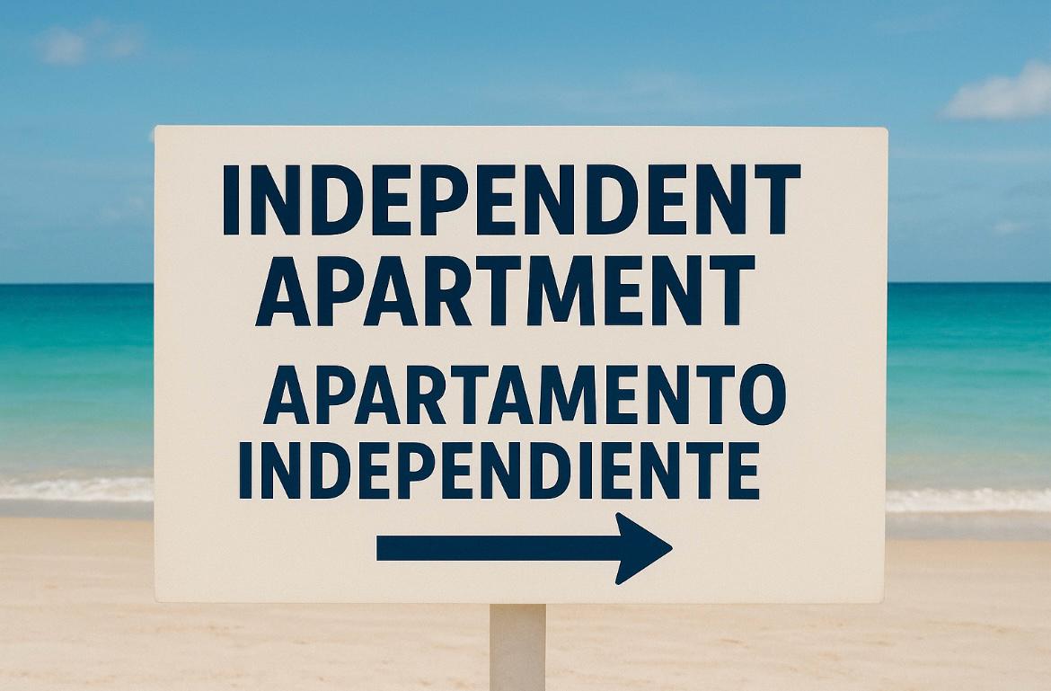 Señalización bilingüe en la playa indicando la dirección de apartamentos independientes.