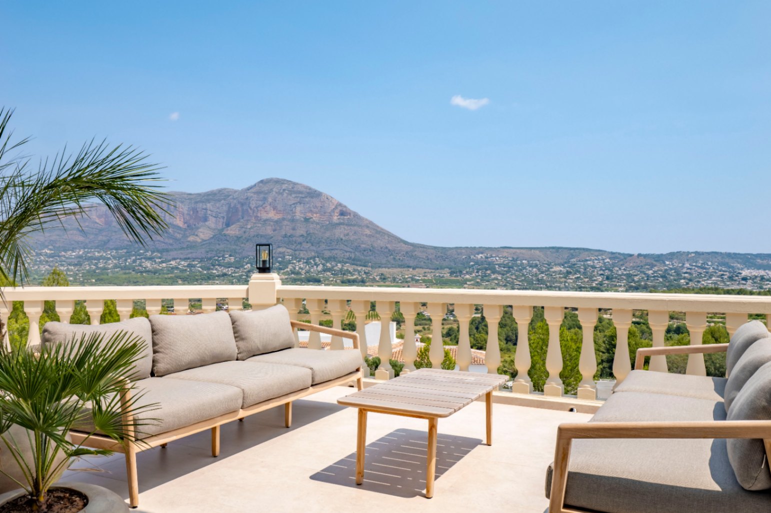 Terraza con balaustrada clásica, mobiliario de exterior en madera y vistas panorámicas a la montaña.