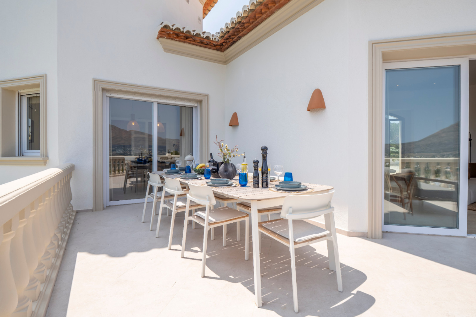 Terraza con comedor al aire libre, mesa de madera clara y vistas panorámicas en Jávea.
