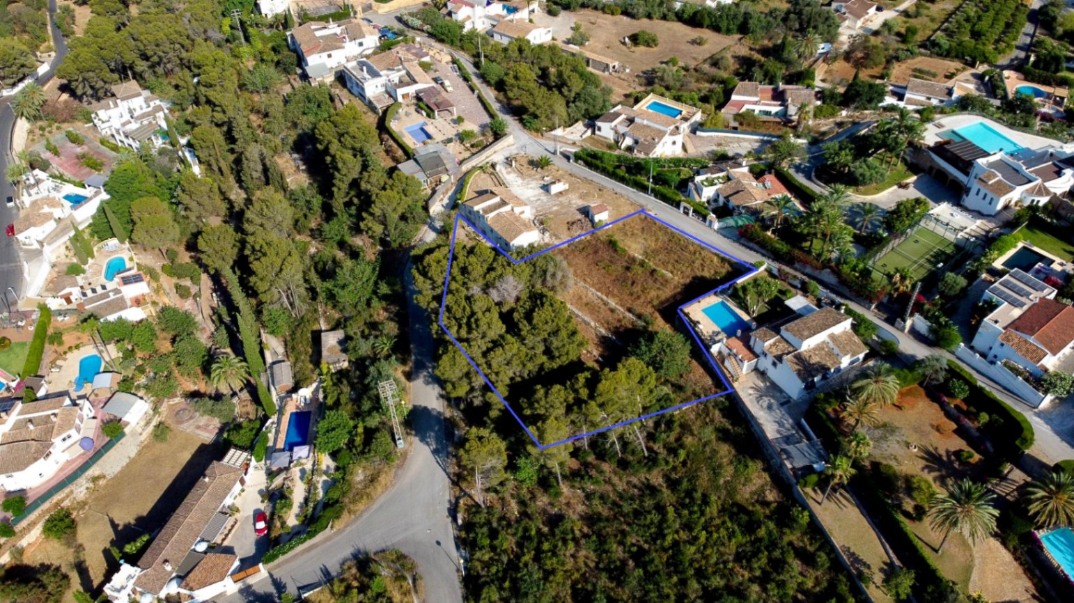 Vista aérea perimetrada de la parcela urbana de 1.908 m², destacando su zona arbolada con pinos y su ubicación en una zona residencial consolidada de Jávea.