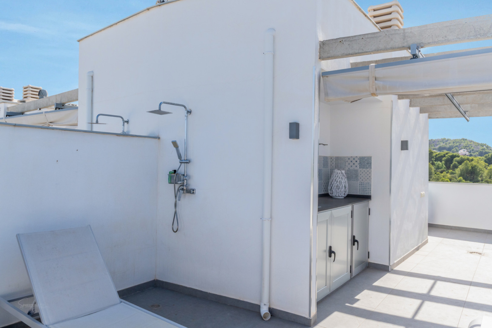 Terraza privada en la azotea con ducha exterior, cocina de verano equipada con armarios blancos y vistas despejadas a la montaña.