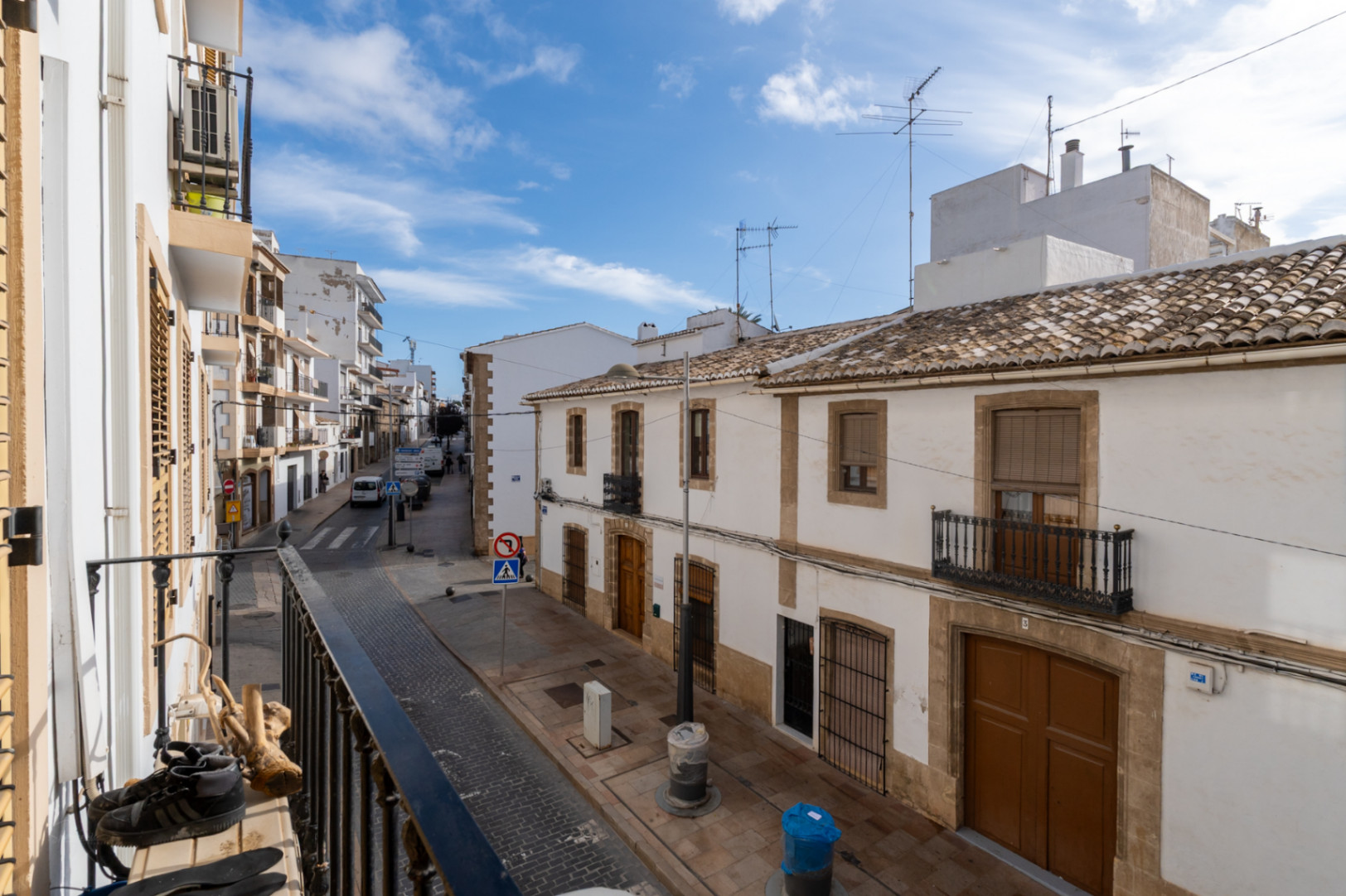 Vista desde el balcón hacia una calle del casco antiguo de Jávea, mostrando fachadas blancas tradicionales, tejados de teja y detalles arquitectónicos en piedra natural.