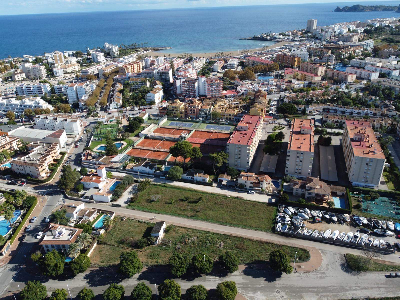 Vista aérea de la parcela estratégica en Jávea, ubicada junto al club de tenis y con vistas despejadas hacia la playa del Arenal y el mar Mediterráneo.