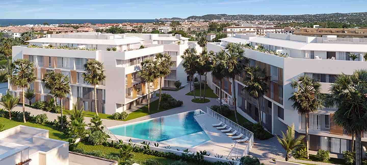 Vista elevada del complejo residencial moderno con piscina central, jardines paisajísticos con palmeras y vistas panorámicas hacia el mar Mediterráneo en Jávea.
