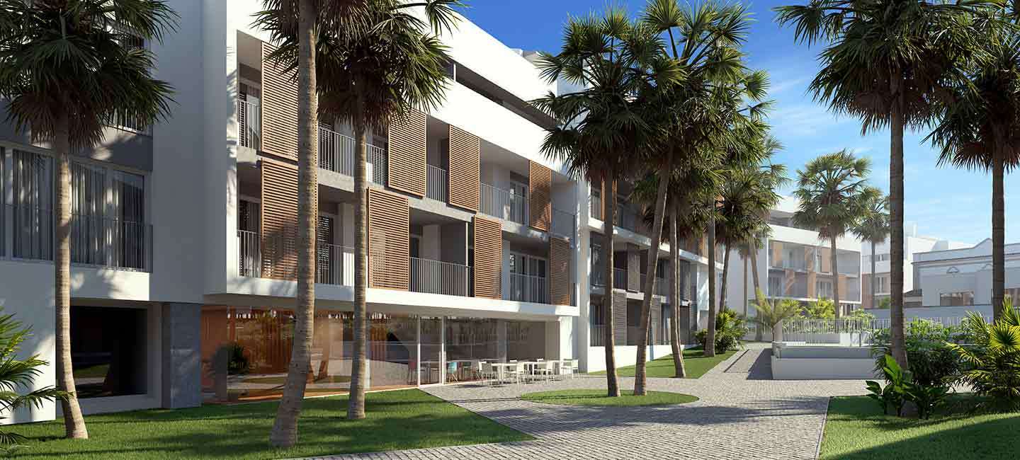 Fachada blanca moderna con contraventanas de madera en los balcones, rodeada de jardines con palmeras y una terraza social pavimentada.