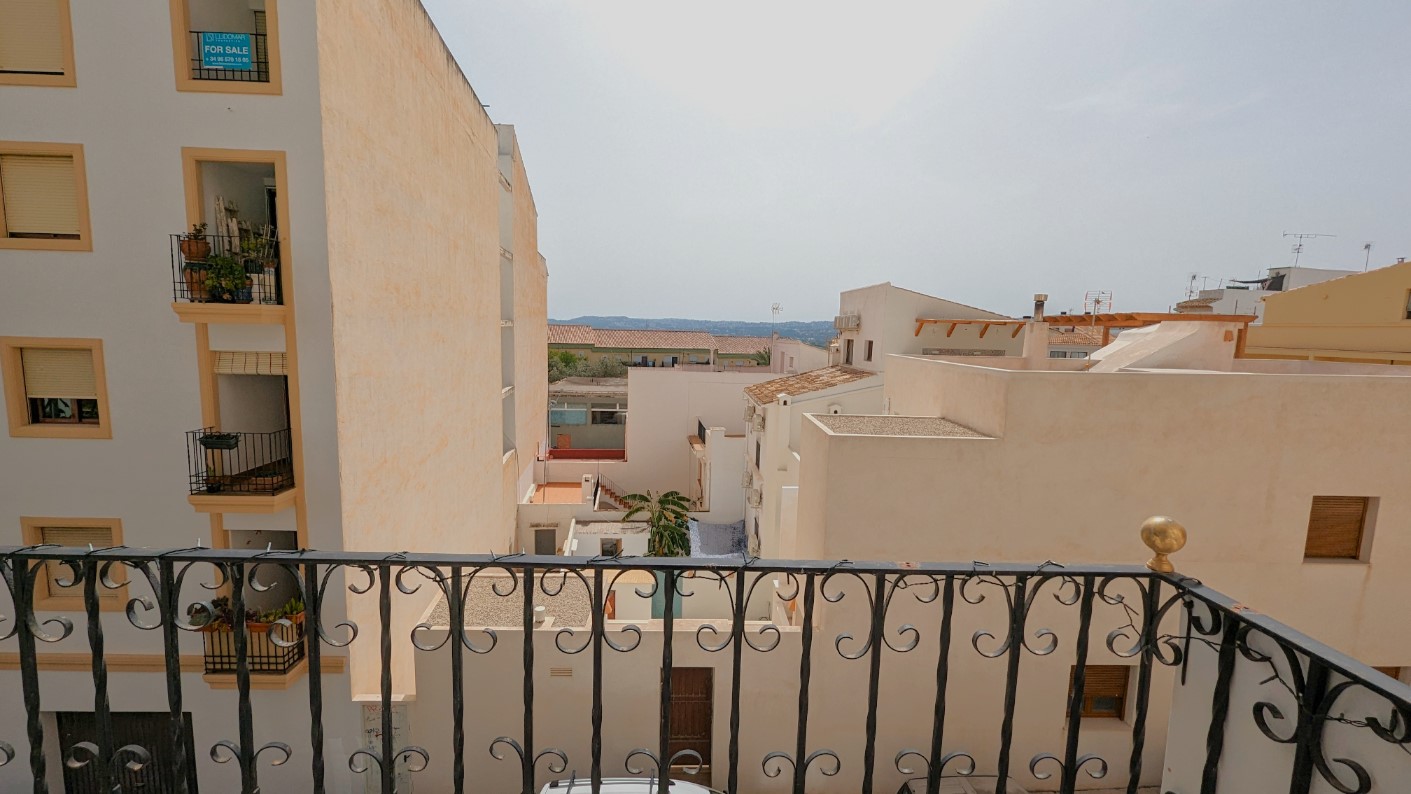 Vista desde el balcón con barandilla de hierro forjado, orientada hacia los tejados del casco antiguo de Jávea y el horizonte montañoso al fondo.