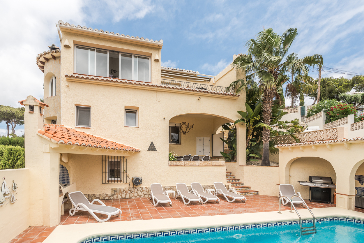 Exterior de la villa con orientación sur, piscina de 8x4m, terraza de terracota con tumbonas y una naya cubierta junto a la zona de barbacoa.