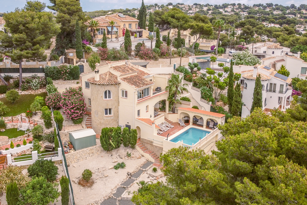 Vista aérea de la villa orientada al sur con torre de piedra, terrazas en varios niveles y piscina de 8x4m con zona de barbacoa cubierta y solárium.