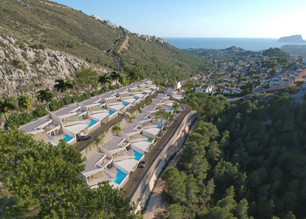 Perspectiva aérea de dieciséis villas modernas escalonadas en Benitachell, cada una con piscina privada y vistas panorámicas hacia la costa mediterránea y el Peñón de Ifach.