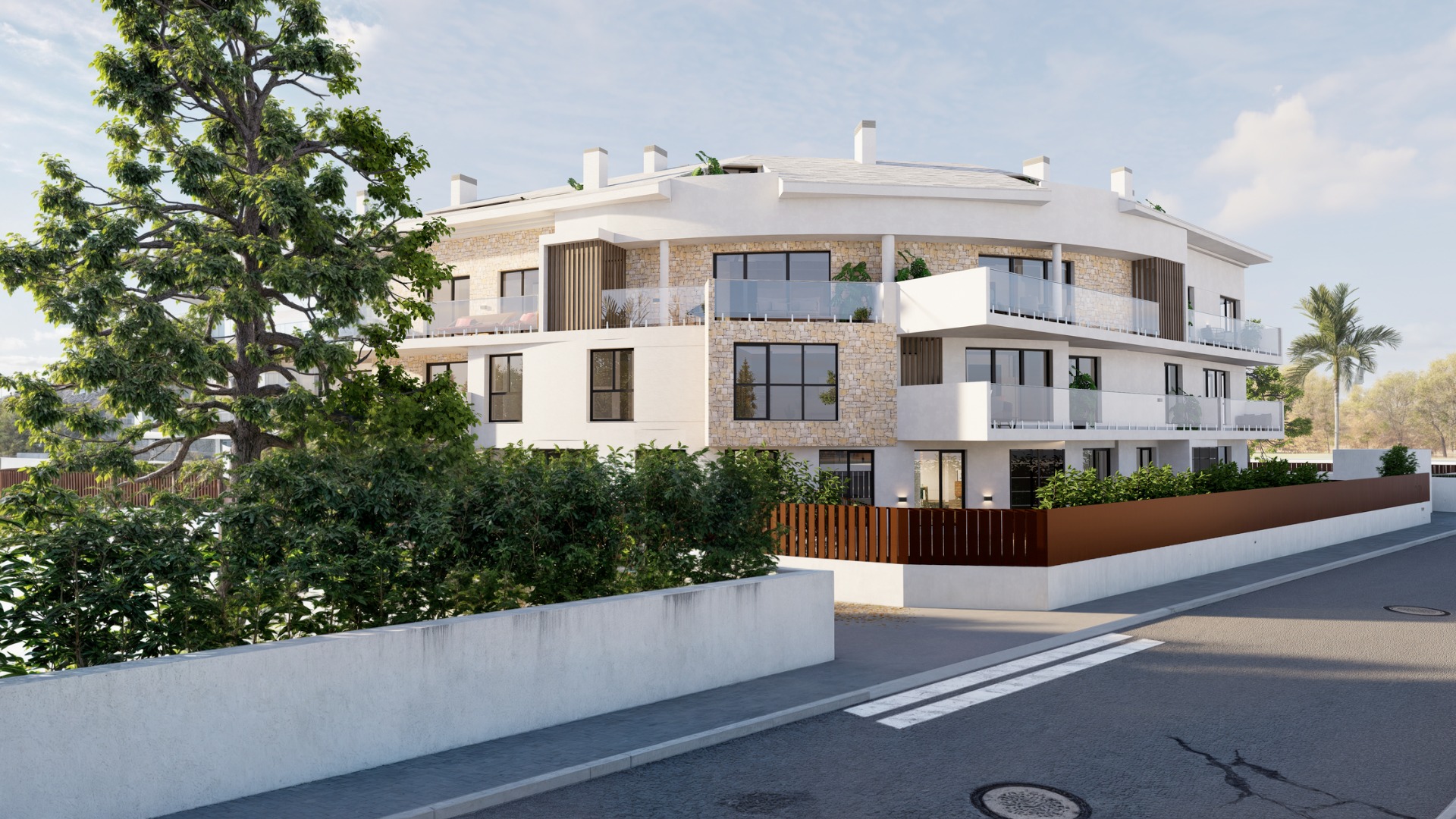 Edificio residencial de tres niveles con fachada curva, acabados en piedra natural, terrazas con barandillas de vidrio y cerramiento perimetral integrado.