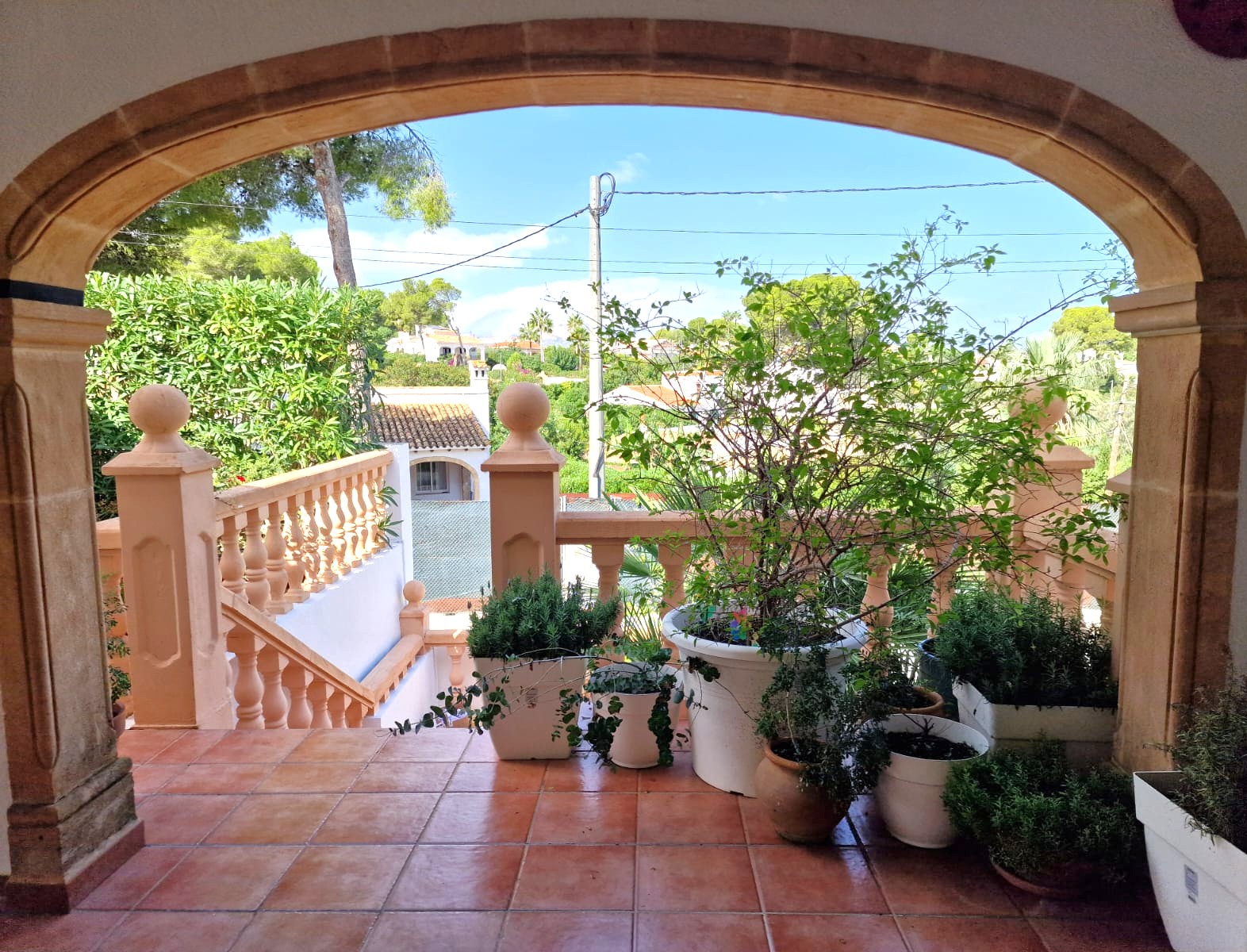Terraza enmarcada por un arco de piedra Tosca tradicional, con suelos de barro, plantas mediterráneas y vistas despejadas al entorno de Toscal.