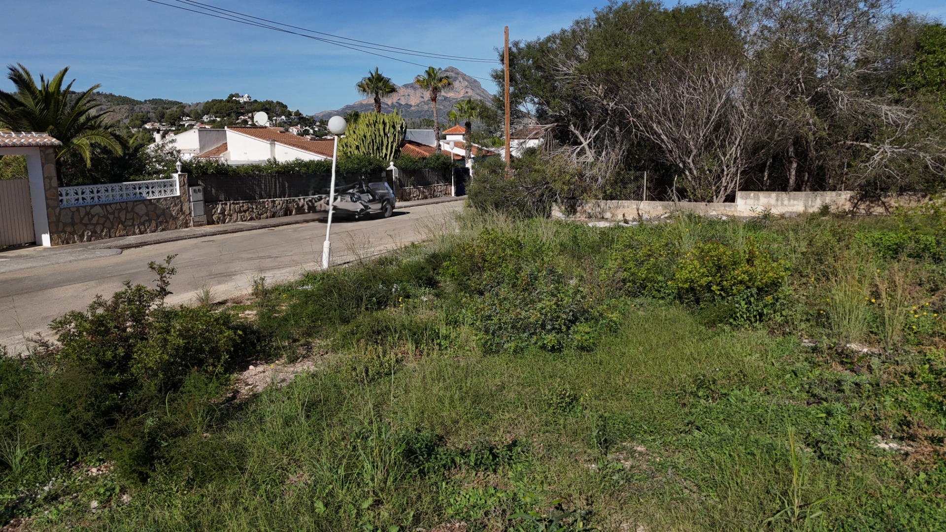 Parcela llana en Pinosol, Jávea, con acceso directo por calle asfaltada y vistas despejadas al macizo del Montgó en un entorno residencial consolidado.