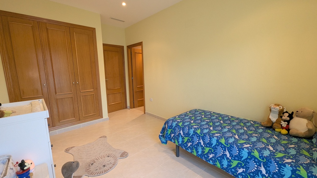 Dormitorio infantil con armario empotrado de madera de cuatro puertas, suelos de gres y aire acondicionado por conductos integrado.