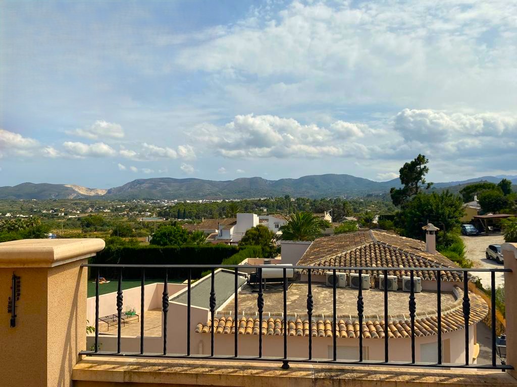 Vistas panorámicas al campo y las montañas desde la terraza, delimitada por una barandilla de hierro forjado tradicional.