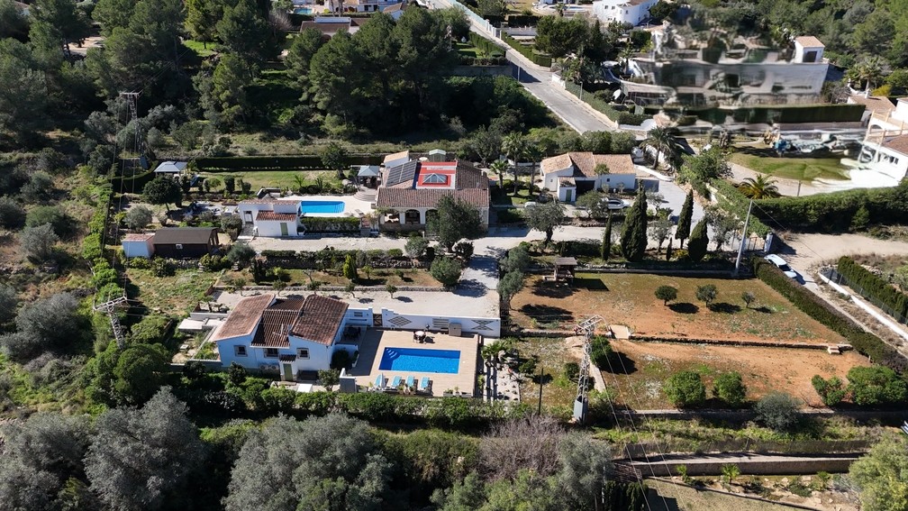 Vista aérea de la parcela de 4.600 m² con dos villas independientes, piscinas privadas, una cabaña de madera y la casa principal con paneles solares y cúpula de cristal.