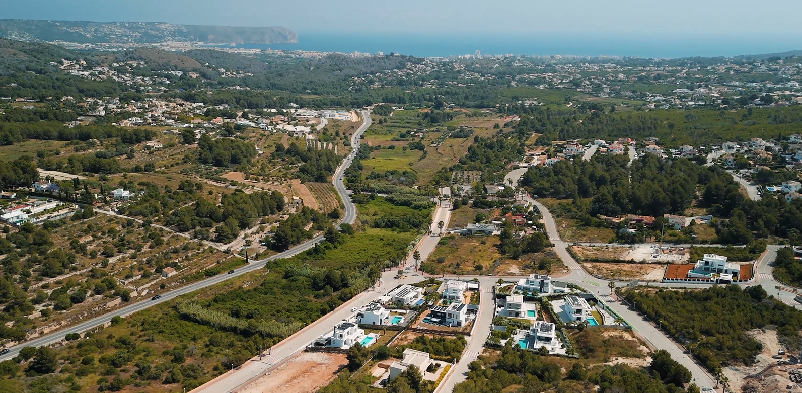 Vista aérea de la zona residencial Villas del Vent en Jávea, mostrando villas modernas y parcelas con vistas panorámicas al mar Mediterráneo y la costa.