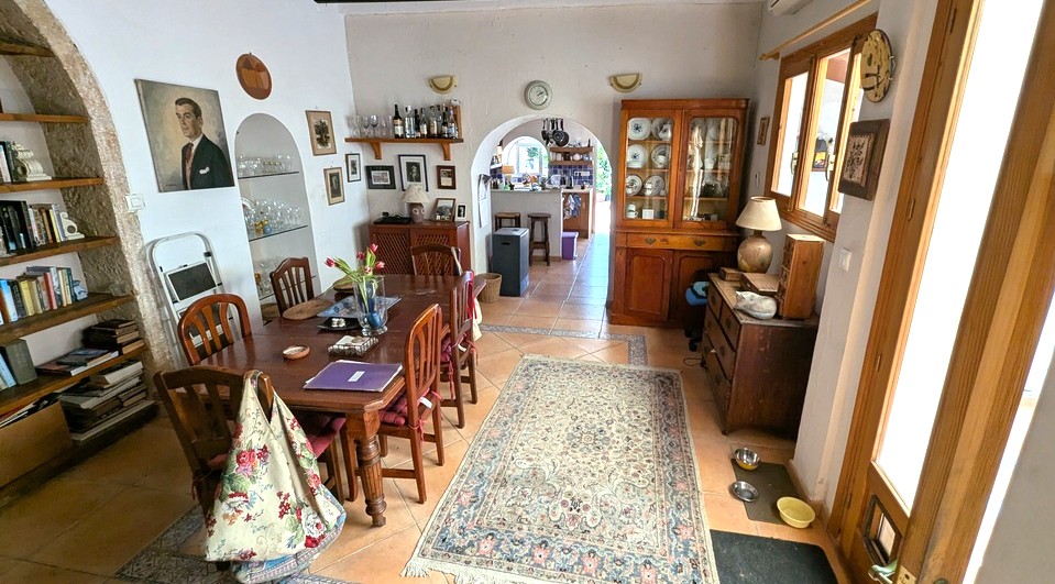 Amplio comedor con suelos de terracota, mesa de madera y arcos de piedra Tosca original con estanterías integradas, conectando directamente con la cocina.