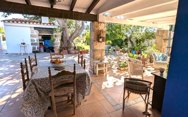 Naya orientada al sur con pilares de piedra Tosca, vigas de madera a la vista y zona de comedor exterior junto al jardín y la cocina de verano.