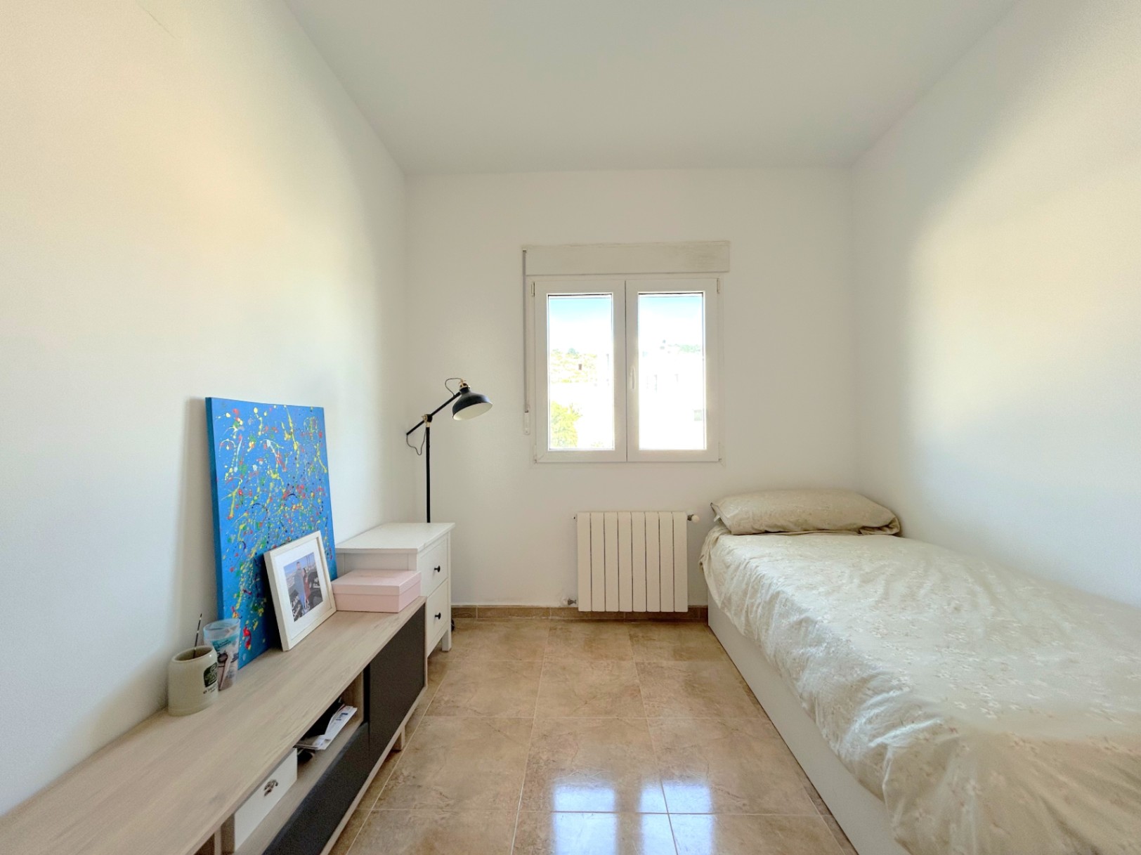 Dormitorio luminoso con suelos de gres, calefacción por radiador y ventana de doble acristalamiento que aporta abundante luz natural.