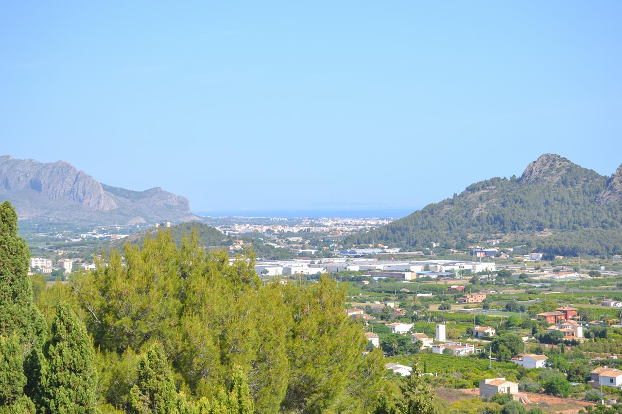 Vistas panorámicas despejadas desde la propiedad hacia el valle y el mar Mediterráneo en el horizonte, enmarcadas por montañas y pinos autóctonos.