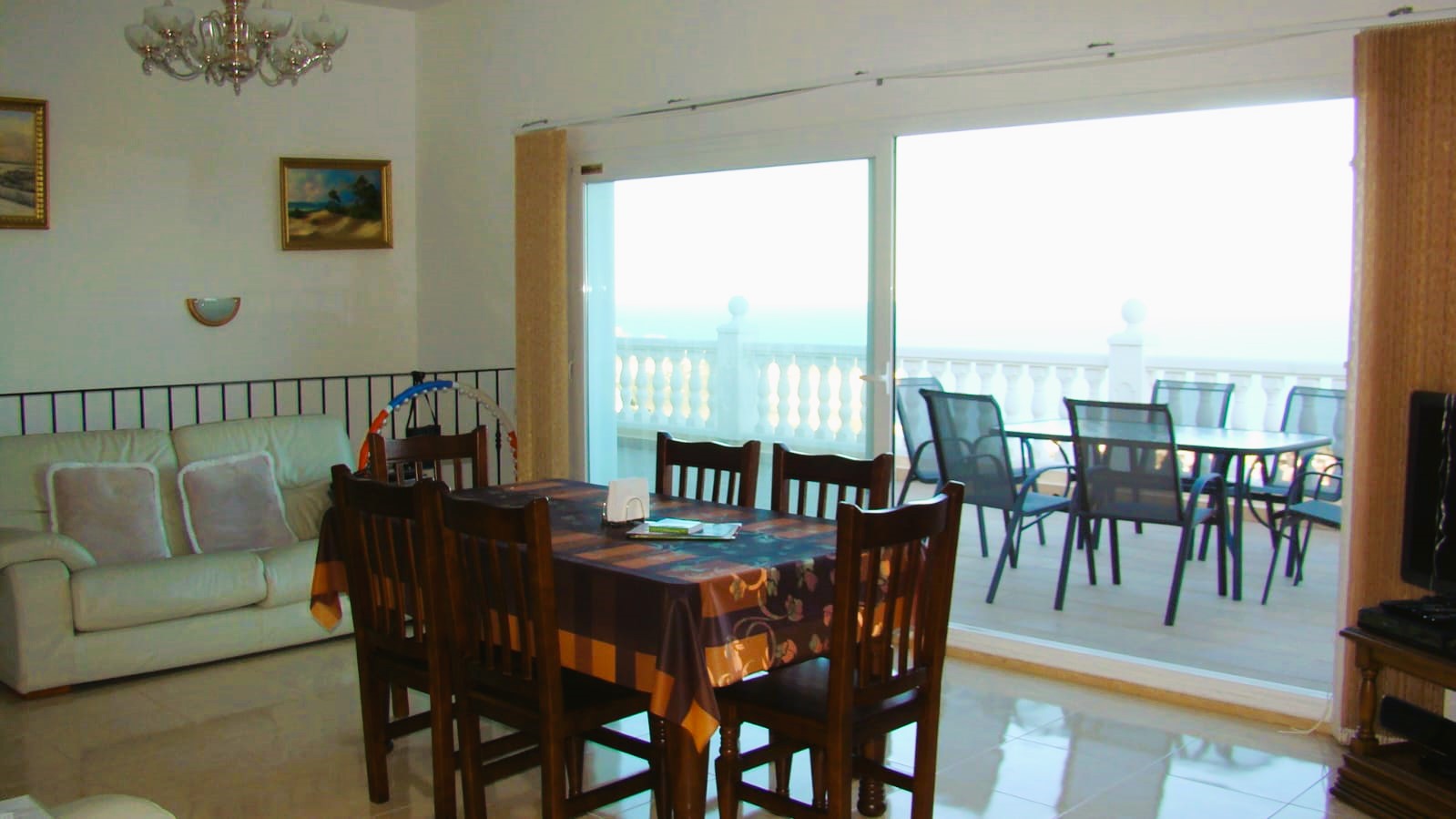 Comedor luminoso con mesa de madera y acceso a la terraza con vistas al mar.