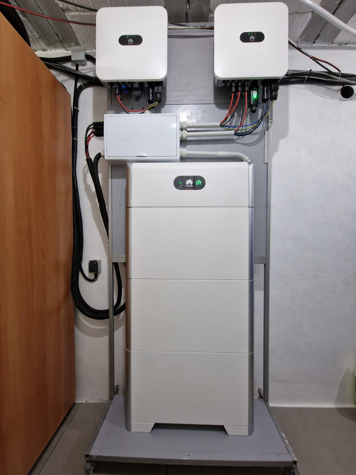 Instalación de batería y reguladores solares Huawei en sala técnica. Cableado visible.