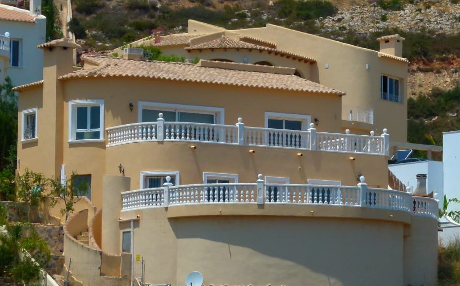 Vista exterior de villa con balcones curvos y barandillas blancas en Cumbre del Sol.
